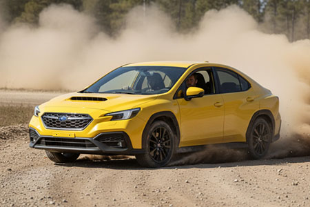 Yellow coloured SUBARU-WRX on a dusty rally track